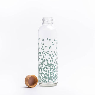 Transparente Glasflasche mit türkisfarbenen Punkten, 0,7 l Volumen, neben einem Korkverschluss.
