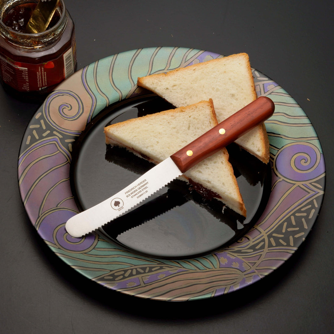 Buckelsmesser auf einem bunten Teller mit Brotscheiben und Marmelade, ideal für das Frühstück.