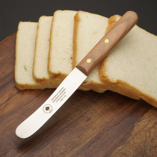 Buckelsmesser aus Solingen mit Holzgriff, ideal für frisches Brot und Frühstück, auf Holzbrett mit Toastscheiben.